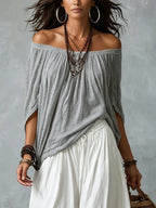 Top grigio scollato con spalle scoperte e ampi pantaloni bianchi lanterna