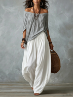 Top grigio scollato con spalle scoperte e ampi pantaloni bianchi lanterna