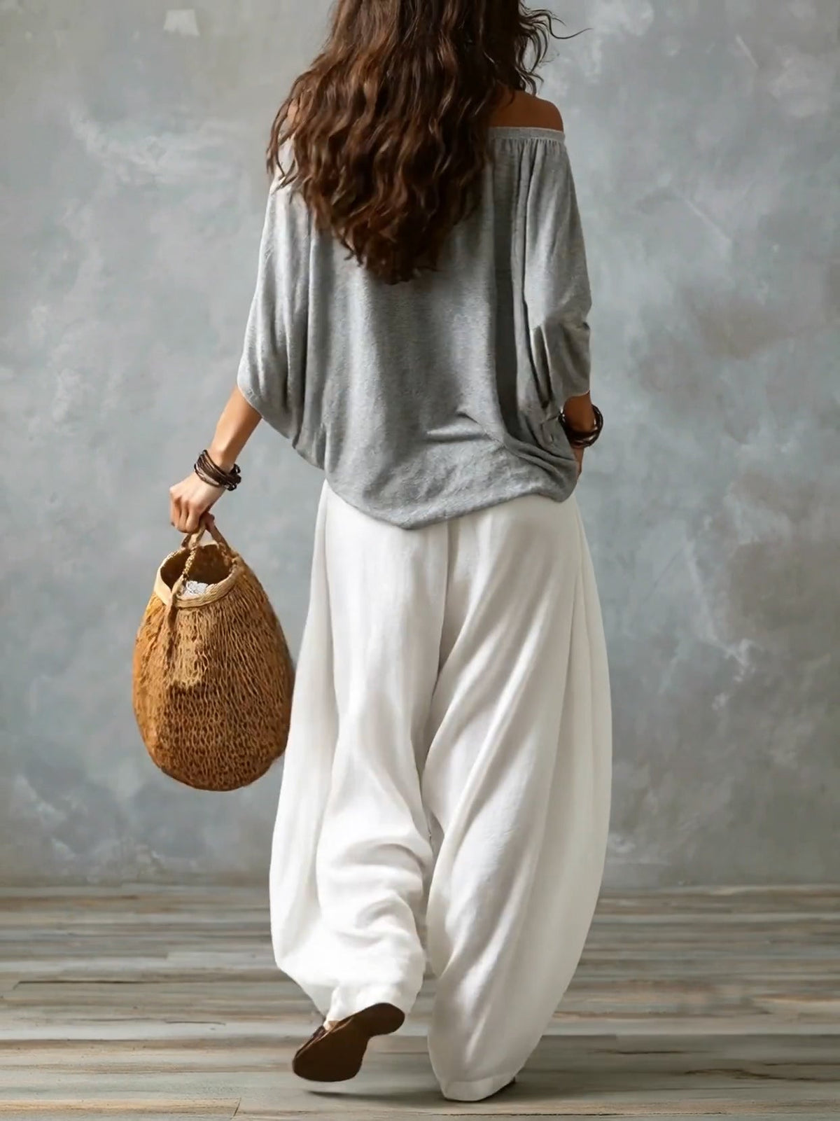 Top grigio scollato con spalle scoperte e ampi pantaloni bianchi lanterna